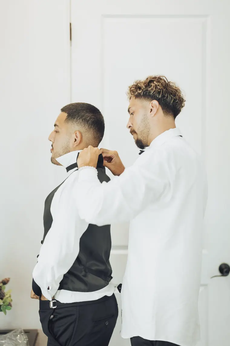 A groomsman having his bow tie tied