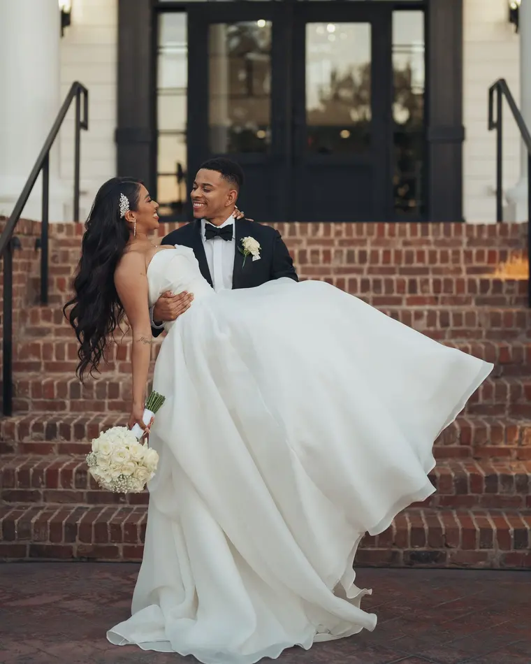 Carrying her down the steps, dress flying