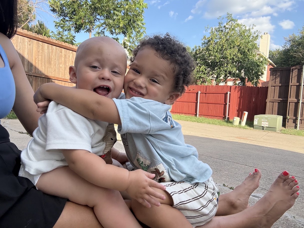 The two boys hugging each other outside in the backyard