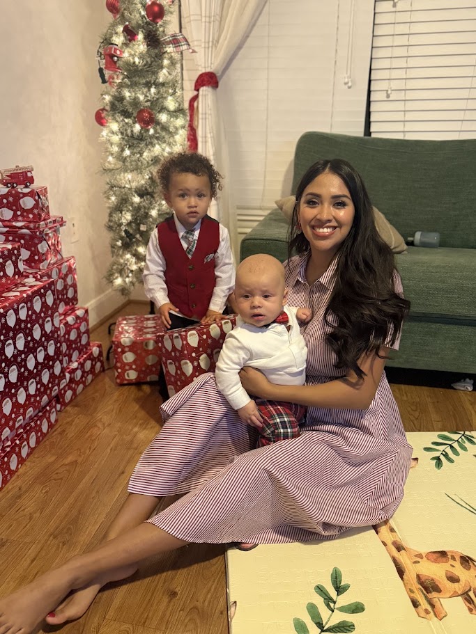 Demonte's wife holding their baby with their older son beside the Christmas tree